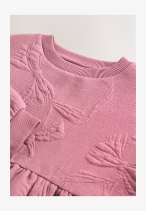 Ružičasti pleteni džemper s teksturiranim cvjetnim uzorcima, ovratnikom u rebrastom kroju i naboranim detaljima tkanine na rubu i rukavima.