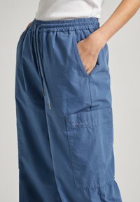 Pantaloni cargo blu realizzati in tessuto leggero, dotati di una cintura elastica, tasche laterali e una tasca a toppa con il logo "Pepe Jeans".