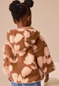 Bruin en roze fleecejack met bloemenpatroon en capuchon, met een zachte textuur en een losse pasvorm. Voorzien van een kangoeroezak aan de voorkant.