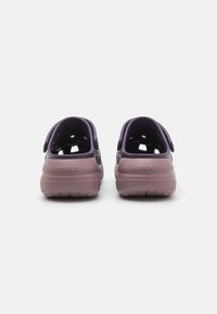 Des Crocs violets et gris clair avec un design moulé, en matériau léger, à talon ouvert et avec des trous de ventilation pour la respirabilité.
