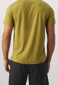 Camiseta de manga corta verde oliva hecha de un tejido transpirable. Presenta un escote redondo, dobladillo recto y un acabado suave y texturizado.