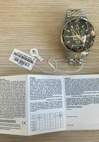 Orologio Maserati con bracciale in acciaio inossidabile dorato e argentato, quadrante nero con logo e dettagli del cronografo. Include la scheda di garanzia.