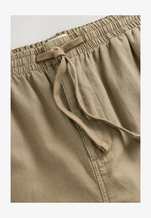 Bermuda khaki con vita elastica, cordino in tessuto e una texture liscia. Presenta dettagli di cucitura e una tasca standard.