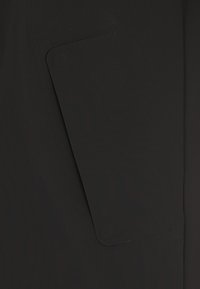 Tessuto nero caratterizzato da una texture liscia e una tasca rettangolare con bordi arrotondati, integrata perfettamente nel design.