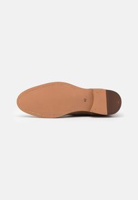 Semelle d'une chaussure habillée en cuir marron avec des coutures visibles, taille 42 marquée près du talon sur un fond blanc.