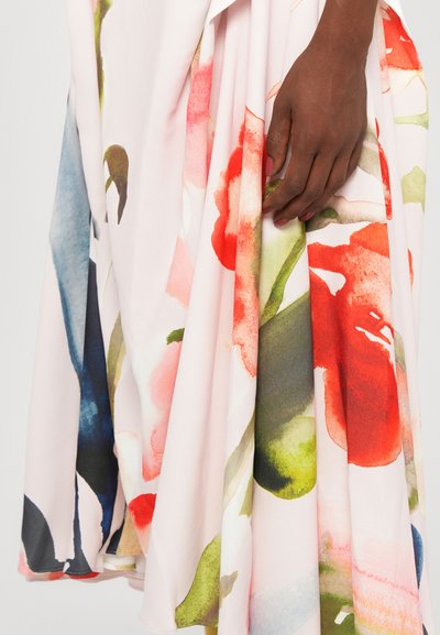 Kukallinen mekko, jossa on vaaleanpunaista kangasta, johon on painettu akvarellityylisiä kuvioita punaisilla, vihreillä ja sinisillä sävyillä. Mekko valuu elegantisti pehmeällä tekstuurilla.