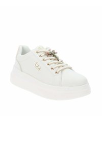 Zapatilla blanca con una suela gruesa blanca, que presenta detalles dorados y adornos decorativos en forma de flores en colores pastel en los cordones.
