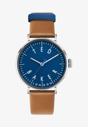 Ronde horloge met een blauwe wijzerplaat, witte markers, zilveren wijzers en een bruine leren band. Contrasterende blauwe leren accent bovenaan.