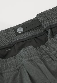 Shorts à rayures gris avec une taille élastique, une fermeture à bouton et une doublure intérieure lisse. Détails cousus le long des bords.