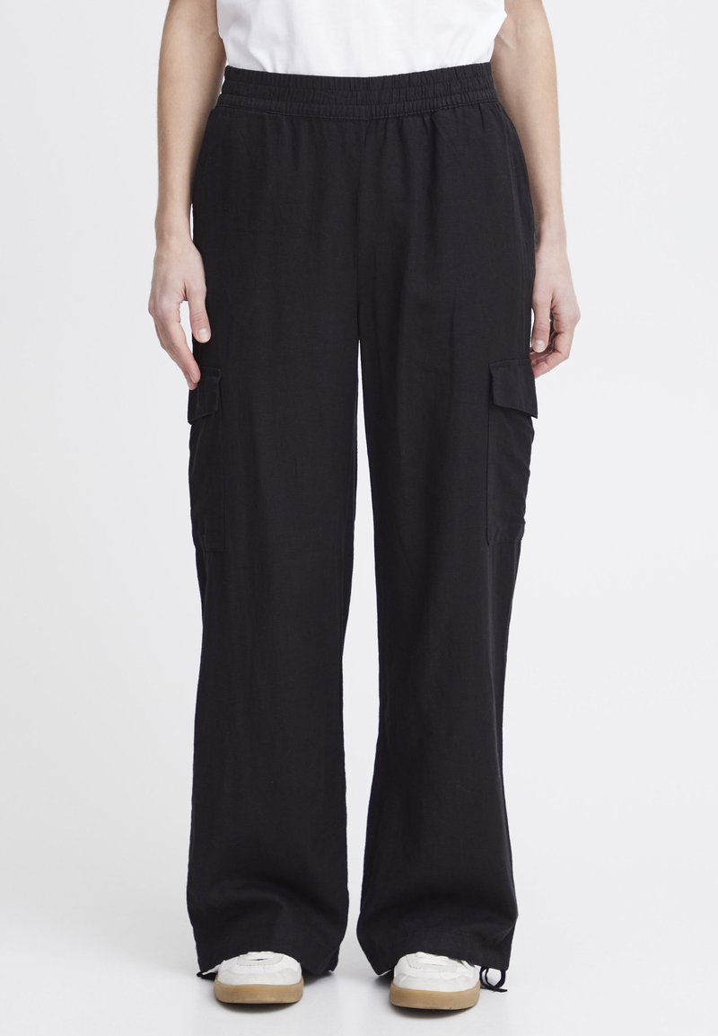 Pantalons cargo noirs en tissu doux, dotés d'une taille élastique, de poches latérales et d'une coupe ample et décontractée. Les accents incluent des poches cargo latérales.