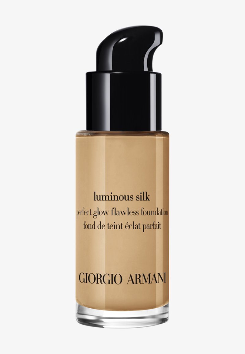 Giorgio Armani Luminous Silk foundation i en transparent glasflaska med en svart pump, har en gyllene vätska och en elegant design.