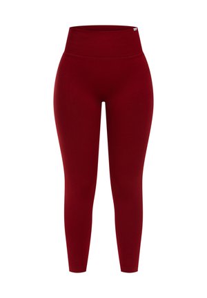 Leggings rouges en tissu lisse et élastique. Conception taille haute avec jambes ajustées, sans motifs ni logos visibles.