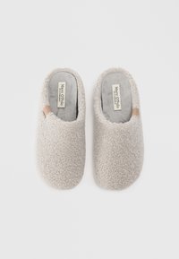Beige, pluizige slippers met een zachte textuur en afgeronde vorm. Beschikt over een tan accent op de bovenkant en gelabelde zolen.