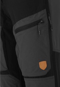Zwarte en grijze broeken met een ritszak, gestructureerde stof en een tan leren logo patch. Ontworpen voor duurzaamheid en functionaliteit.