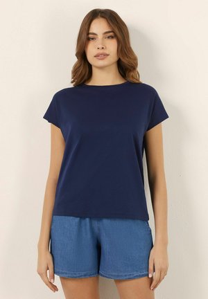 Marineblauwe korte mouwen t-shirt, met een ronde halslijn, gemaakt van zachte stof. In combinatie met lichte denim korte broeken met een elastische taille.