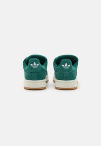 Grüne Wildledersneaker mit niedrigem Profil und weißer Gummisohle. Zu den Merkmalen gehören ein gepolsterter Kragen und ein ikonisches weißes Logo an der Ferse.
