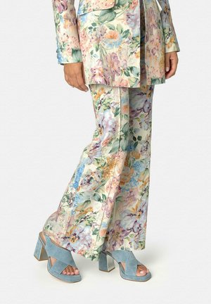 Pantalones acampanados con estampado floral y blazer a juego, combinados con sandalias de tacón bloque de ante azul claro con tiras cruzadas y dedos descubiertos.