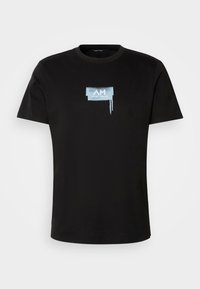 Camiseta de algodón negra con mangas cortas que presenta un logo gráfico en color azul claro en el pecho, diseño pintado con goteos en la parte inferior.