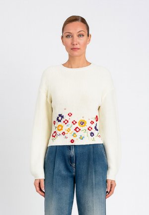 Maglione bianco lavorato a maglia con maniche lunghe, caratterizzato da ricami floreali multicolori in vita. Texture morbida e vestibilità rilassata.