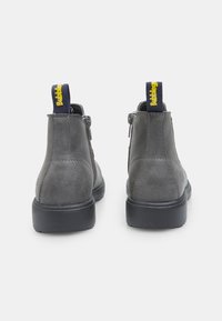 Botas de tobillo de gamuza gris con una textura suave, que incluyen un cierre de cremallera y una tira de tirón de marca amarilla en la parte posterior. Suela de goma negra.
