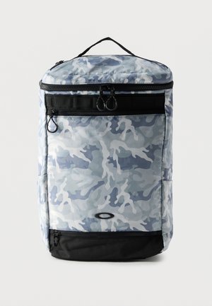 Rucsac dreptunghiular cu model camuflaj albastru și gri deschis, secțiune inferioară neagră, buzunare frontale cu fermoar și mâner superior pentru transport.