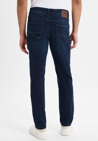 Dunkelblaue Denim-Jeans mit geradem Bein, versehen mit Gesäßtaschen mit gestickten Akzenten und einem markierten Lederpatch am Bund.