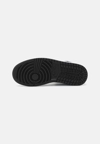 Svart sulan i gummi på sneakers med cirkulära och linjära mönster. Har en central cirkulär vridpunkt och en upphöjd strukturerad logotyp.