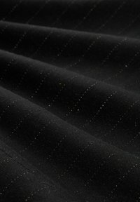 Czarna tkanina o fakturowanej powierzchni, z delikatnymi srebrnymi prążkami, tworząca warstwowy wygląd z miękkim połyskiem.