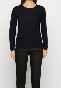 Zwarte lange mouwen gebreide trui met een ronde halslijn, een gladde textuur en een aansluitend ontwerp, gecombineerd met donkere broek.