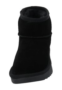 Zwarte suède enkellaars met een ronde neus, zachte voering en een textuurrubberzool. Voorzien van een zijnaad en minimalistisch ontwerp.