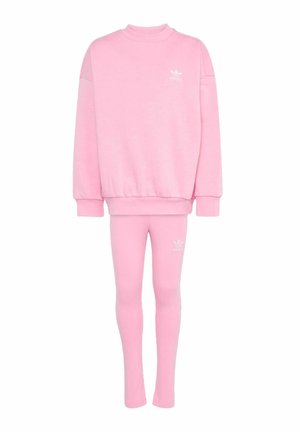 Light pink Adidas tracksuit set with oversized sweatshirt and fitted leggings, featuring small white Adidas logo on chest and thigh.