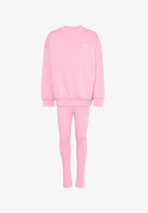 Lyserødt Adidas træningssæt med oversized sweatshirt og tætsiddende leggings, med lille hvid Adidas-logo på bryst og lår.