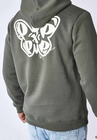 Felpa verde oliva con una grande grafica di una farfalla bianca e firma sul retro. Presenta un cappuccio con coulisse e polsini a coste.
