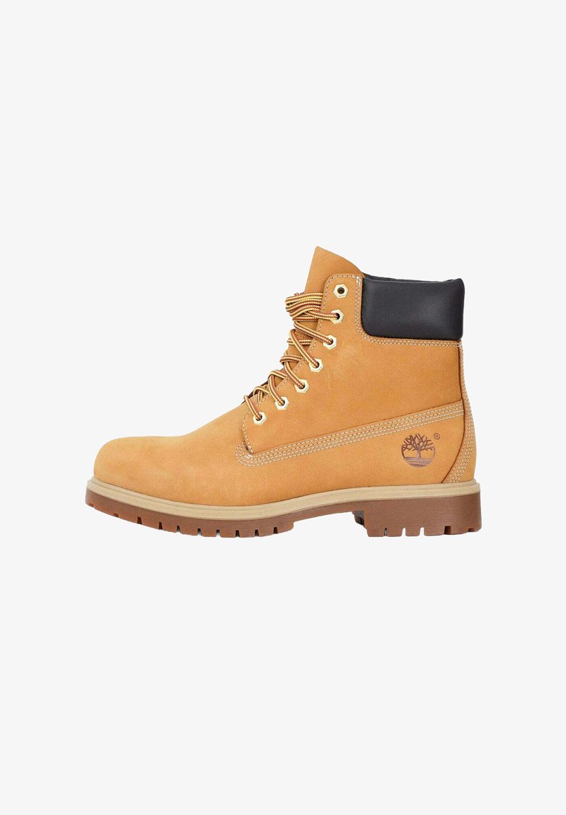 Stivale in suede color sabbia con colletto imbottito nero, occhielli in metallo e suola in gomma, caratterizzato da cuciture tono su tono e un logo sul lato.