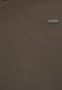 Brun texturerad tyg med ett diagonalt revmönster. Innehåller en liten metalltagg med varumärkets namn.