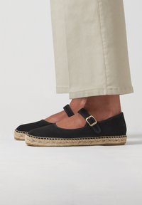Černé semišové espadrilky s kulatou špičkou, kotníkovým páskem a zlatou sponou, s přírodní juty podrážkou.