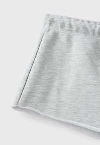 Light gray fabric with visible stitching and a slight folded edge, showing texture and detail of soft knit material.