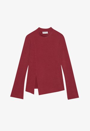 Punane soonikuga pikkade varrukatega särk kõrge kaelusega. Omab asümmeetrist hemmi külgaukudega ja sujuvat tekstuuri. Silt on nähtav seest.