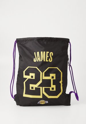 Fekete húzózsinóros táska, amelyen a "JAMES" felirat és a "23" sárga számok láthatók. Lila zsinórkiegészítők és a Lakers logó található az alján. Sima nylon anyag.