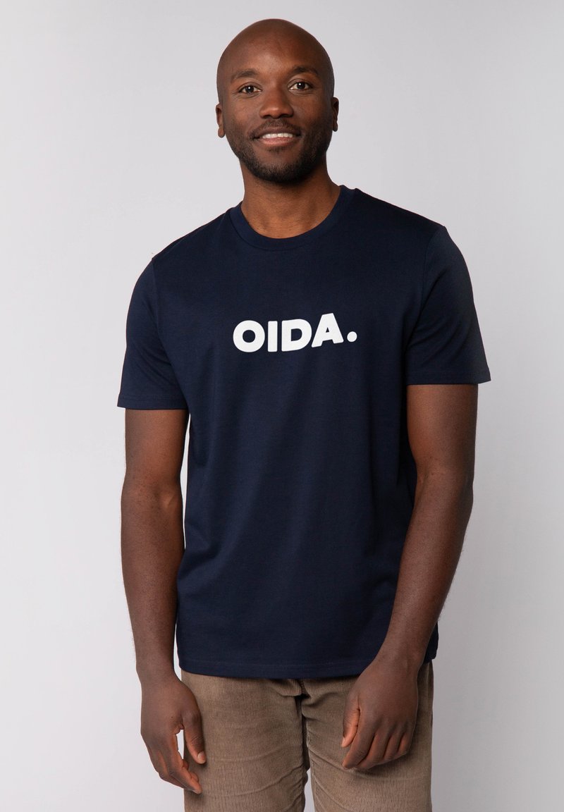 T-shirt navy à manches courtes en coton doux, arborant un texte blanc en gras "OIDA." sur le devant. Design classique à col rond, texture lisse.