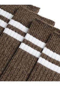 Brune strikkede sokker med tre hvite striper på toppen. Materialet har en teksturert finish med ribbestrikket design gjennom hele.