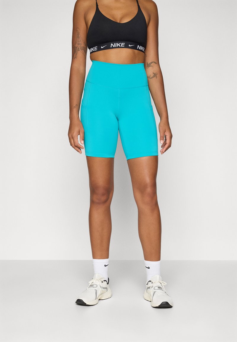 Shorts Nike turcoaz cu talie înaltă și un design elegant. Prezintă o textură netedă și cusături în contrast, însoțite de un sutien sport negru.