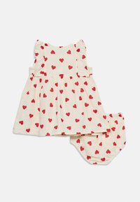 Κρεμ φόρεμα μωρού χωρίς μανίκια με βολάν στους ώμους και ταιριαστά σορτσάκια, και τα δύο με μοτίβο κόκκινες καρδιές.