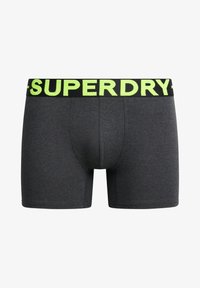 Boxer da uomo grigi con un cinturino nero che presenta il logo "SUPERDRY" verde brillante. Tessuto morbido, design aderente, gambe di lunghezza media.