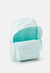 Ljusblå liten ryggsäck med öppen huvudfack och framficka med dragkedja, visad mot en vit bakgrund.