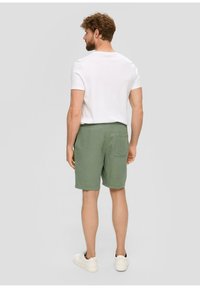 Groene geruite shorts van een textuurstof, met een achterzak, gecombineerd met een effen wit t-shirt en witte sneakers.