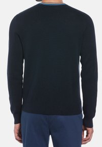 Pull en maille bleu marine avec manches longues, poignets et ourlet côtelés. Présente un accent contrastant bleu et noir autour du col.
