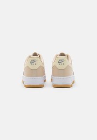 Nike Air sneakers, in light beige and white. Features a smooth leather upper, padded collar, and gum rubber outsole.