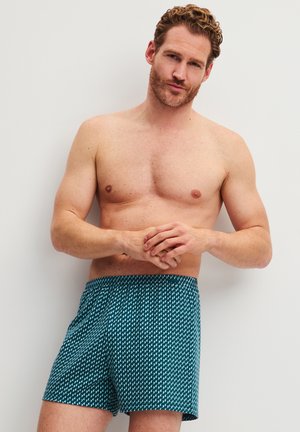 Boxershorts in donker petroleum met een geometrisch patroon. Gemaakt van stof met een gladde textuur en een elastische tailleband voor comfort.