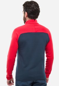 Fleece-Pullover mit hohem Kragen. Rote Ärmel und oberer Rücken, navyblauer unterer Rücken. Glatte Textur, taillierte Passform, keine sichtbaren Beschläge.